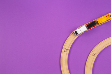Toy train and wooden rails on purple violet background