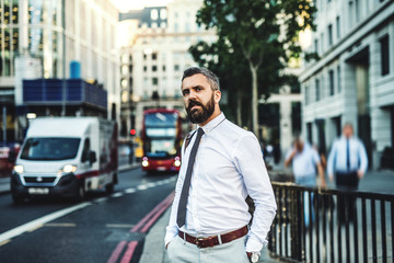 Hipster businessman standing on the street in London next to a busy road.