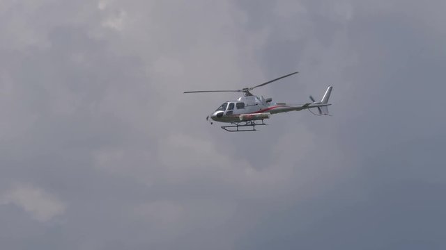 A rescue helicopter with stretcher flying in a cloudy sky