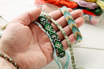 Hand holding different woven friendship bracelet, closeup shot