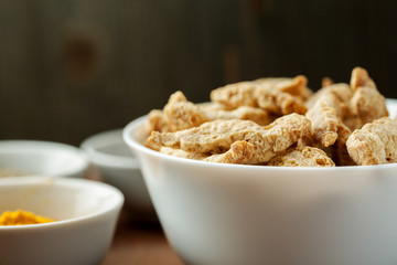 Raw dry soya meat chunks in a white bowl on a wooden table, closeup shot