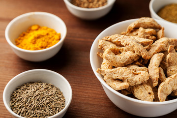 Raw dry soya meat chunks in a white bowl on a wooden table with different species