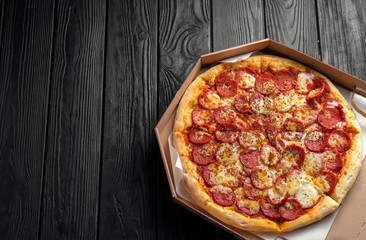 pepperoni pizza on dark black wooden board, top view, place for text, traditional italian pizza
