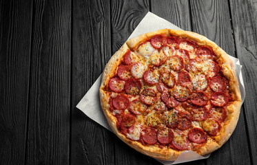 pepperoni pizza on dark black wooden board, top view, place for text, traditional italian pizza