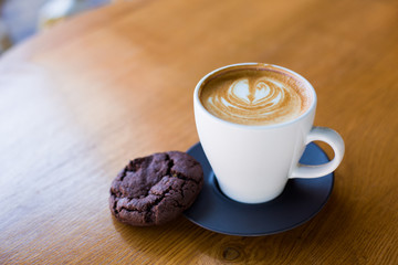 Cup of coffee served with chocolate cookie.