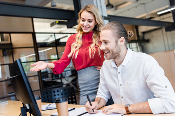 Fototapeta premium businessman and businesswoman working on project together at workplace with computer screen in office