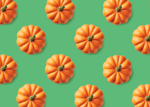 Colorful pattern of orange pumpkins on green background
