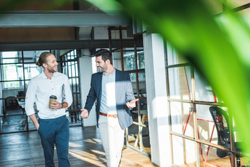Fototapeta premium smiling business colleagues having conversation while walking in hall