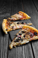 pieces of pizza on dark black wooden board, traditional italian pizza