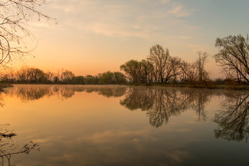 Peaceful farm pond reflecting the sunrise with beautiful fog rising off the water