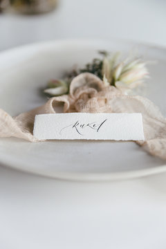 Two floral corsages lying on a plate with a handwritten place card.