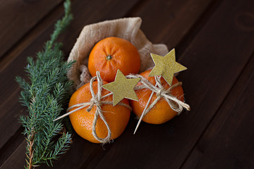 Tangerines with a green branch of a Christmas tree on a dark brown wooden background