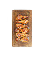 Roasted chicken drumsticks  on a cutting board on a white background