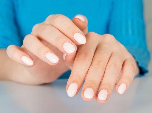 female hand with beige nail design.