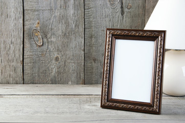 Empty brown picture frame on wooden background.