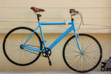 Blue bicycle hanging on pale yellow cement wall
