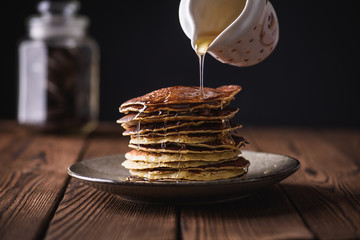 Close up view of homemade pancakes. Stack of pancakes with honey on wooden background.