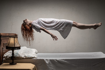 Woman levitating over bed / astral traveling, nightmare, excorcist halloween concept - 229150935