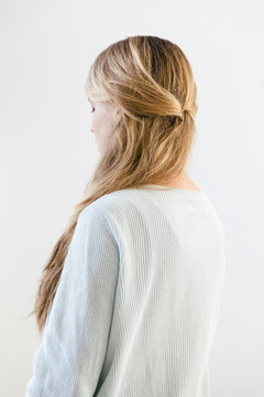 A Woman With Long Straight Dark Blonde Hair Wearing A Light Cotton Knitwear Seen From The Back.