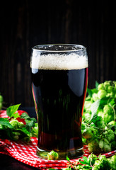 Dark english beer, ale or stout is poured into glass, dark bar counter, space for text, selective focus