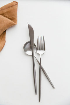 Cutlery randomly styled on a white table.