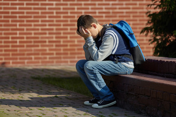 Schoolboy crying in the yard of the school