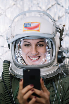 Beautiful female astronaut with mobile phone.