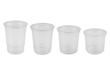 four white transparent plastic glasses stand in a row, different in size, on a white background, isolate
