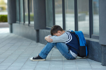 Schoolboy crying in the yard of the school