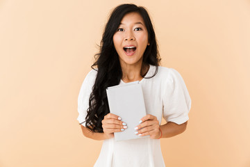 Portrait of an excited asian girl isolated over beige