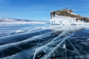 Lake Baikal in winter. Blue smooth ice with cracks near the beautiful iced Cape Kobyliya Golova is a natural landmark of Olkhon Island