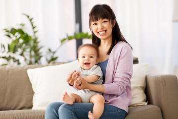 Fototapeta na wymiar family and motherhood concept - happy smiling young asian mother with little baby son at home