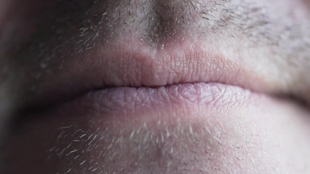 male lips macro shooting. Close-up of a male mouth. He smiles and shows big teeth. There is light stubble on the man is face