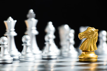 Gold knight chess piece face with silver team on black background (Concept for company strategy, business decision and encounter the problem)