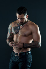 Send message. Handsome fit man send message smartphone. Muscular tattooed athlete look attractive....
