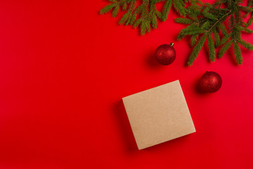 Christmas composition. Fir tree branches, christmas decorations and present gift box on red background