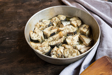 Baked fish mackerel in a pan, on a wooden background. Slices of baked Atlantic mackerel