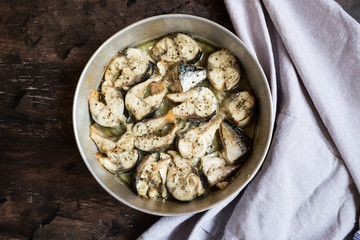 Baked fish mackerel in a pan, on a wooden background. Slices of baked Atlantic mackerel