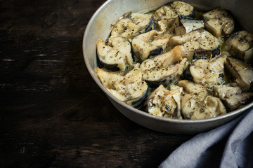 Baked fish mackerel in a pan, on a wooden background. Slices of baked Atlantic mackerel