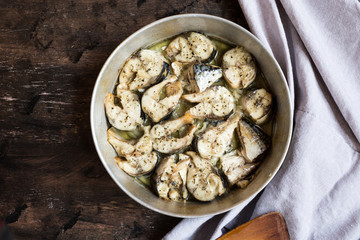 Baked fish mackerel in a pan, on a wooden background. Slices of baked Atlantic mackerel
