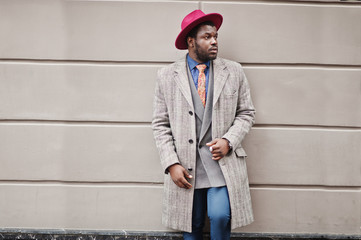 Stylish African American man model in gray coat, jacket tie and red hat.