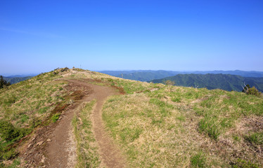 Dirt trail to top of mountain under vibrant blue sky on sunny day