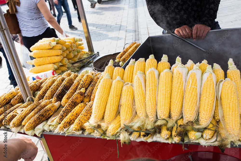 Wall mural fresh boiled and roasted corn is famous street food of istanbul, turkey. grilled corn on the hot sto