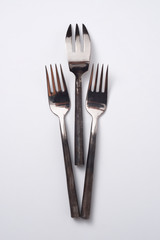 Three metal different vintage forks on a gray background with space for text. Flat lay