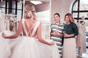 Absolute perfection. Joyful positive women holding glasses with champagne while looking at the bride