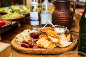 Delicious snacks for beer. Hot hunting sausages on the cheese next to the chips and sauces