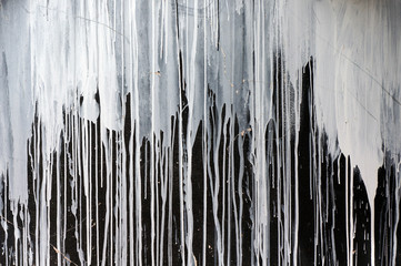 Drips of white paint on black wall.
