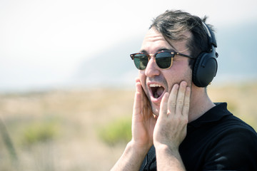 Surprised attractive man wearing sunglasses and headphones