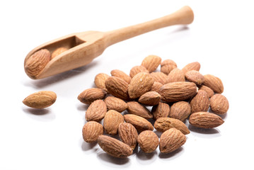 Close-up of pile of roasted, salted almond nuts in a wooden spoon on white background