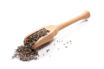 Close-up of pile of raw dark chia seeds in a wooden spoon on white background
